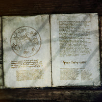 A fictional spell book lays open and filled with strange markings, used as a promotional image for the arcane cipher font