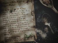 Old book with handwritten text and a silver spoon on a dark surface