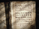 An old book sits open and is filled with old calligraphy, used to promote the Spellbinder font by Aesoterik