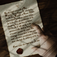 Image of a physical letter prop created for a ttrpg campaign, a player points at medieval calligraphy writing on an ancient looking note