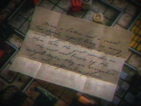 Handwritten letter on a textured surface with dice and game pieces in the background
