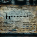 Dgitally manipulated photograph showing an ancient looking dwarven map on a dark wood desk. The map contains part of a floorplan and lots of writing set in a runic font, this is the Fellcarved rune font by Aesoterik