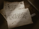 Two old letters with handwritten text on a wooden surface, used as a prop for D&D