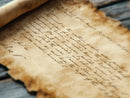 A ttrpg prop of an old, handwritten letter on a wooden surface