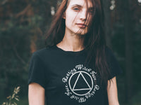 red haired girl wearing a black t-shirt with a white symbol and text against a blurred natural background